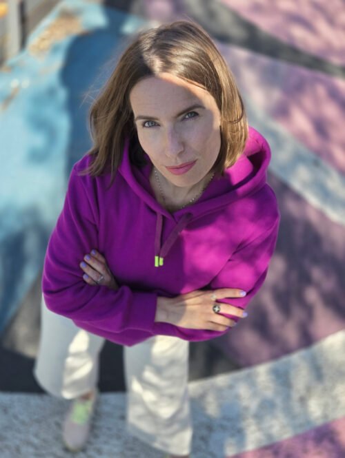 Portrait d’une femme en hoodie fuchsia, bras croisés ; patron couture sweat femme Bauhaus.