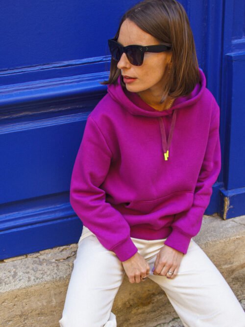 Femme assise en hoodie fuchsia, vue de trois-quarts ; patron sweat femme Bauhaus.