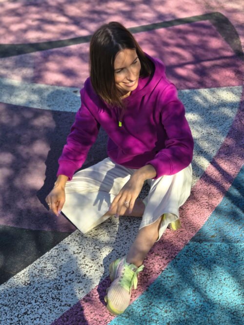 Femme assise au sol portant un hoodie fuchsia ; patron sweat femme Bauhaus.